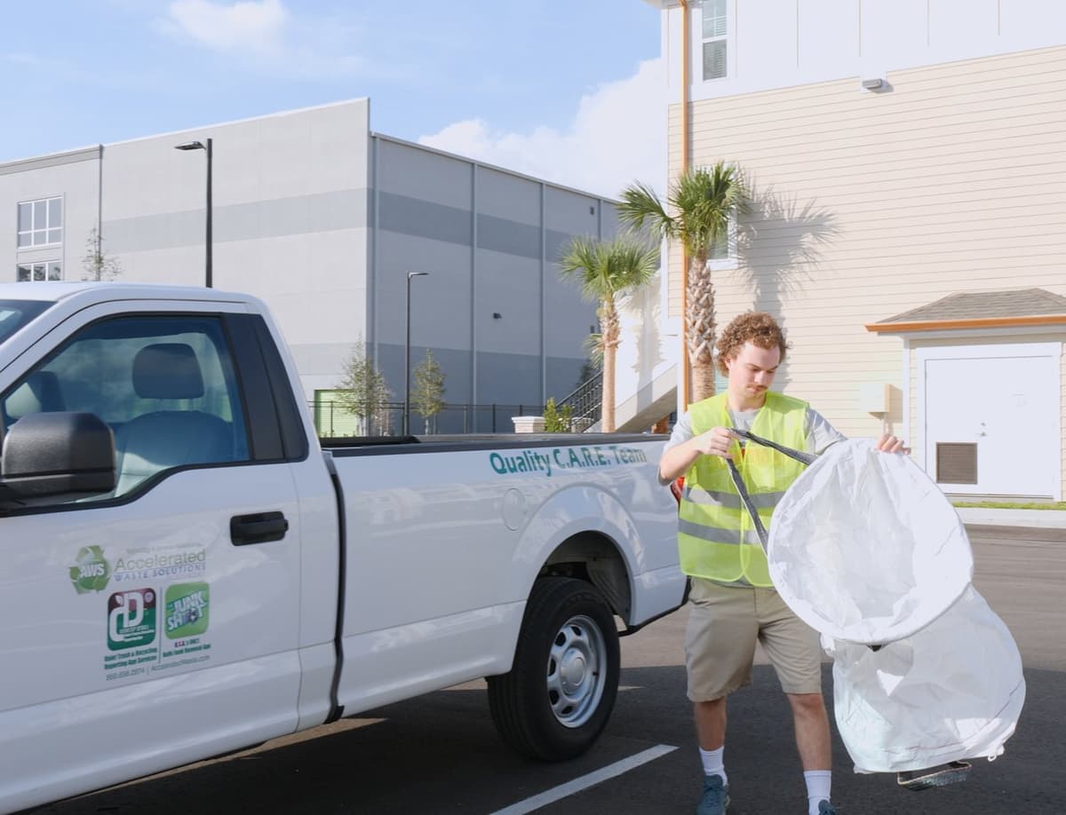 Valet trash porter loading collected trash into service vehicle