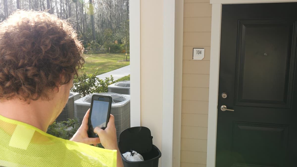 Valet trash porter using app to confirm doorstep pickup